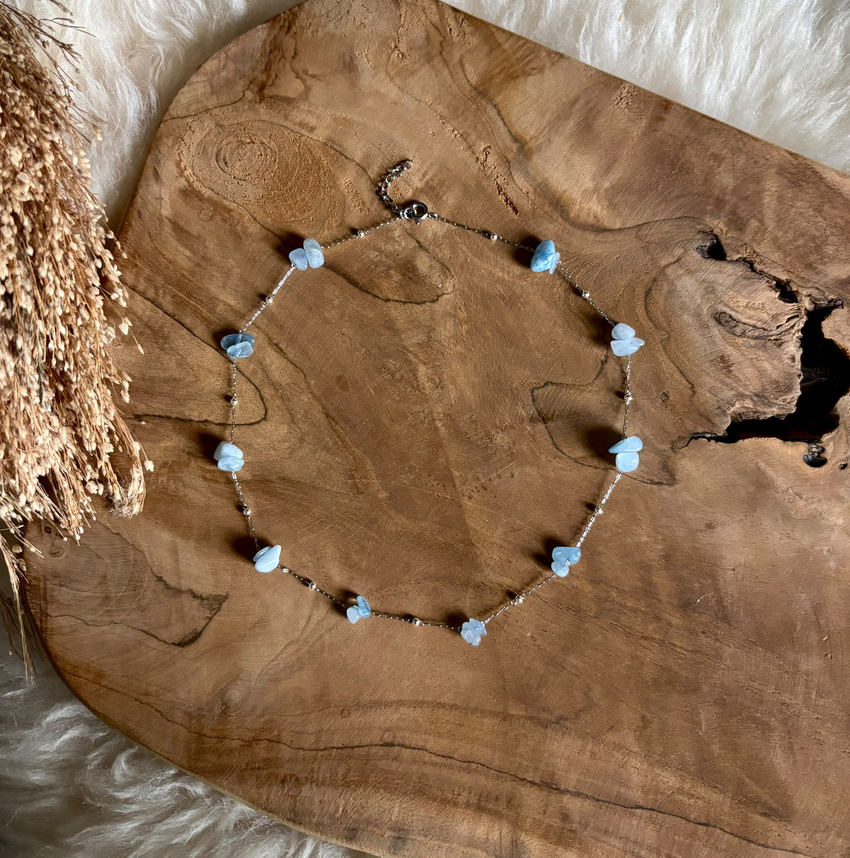Zilverkleurige ketting Lumi met lichtblauwe aquamarijn op hout