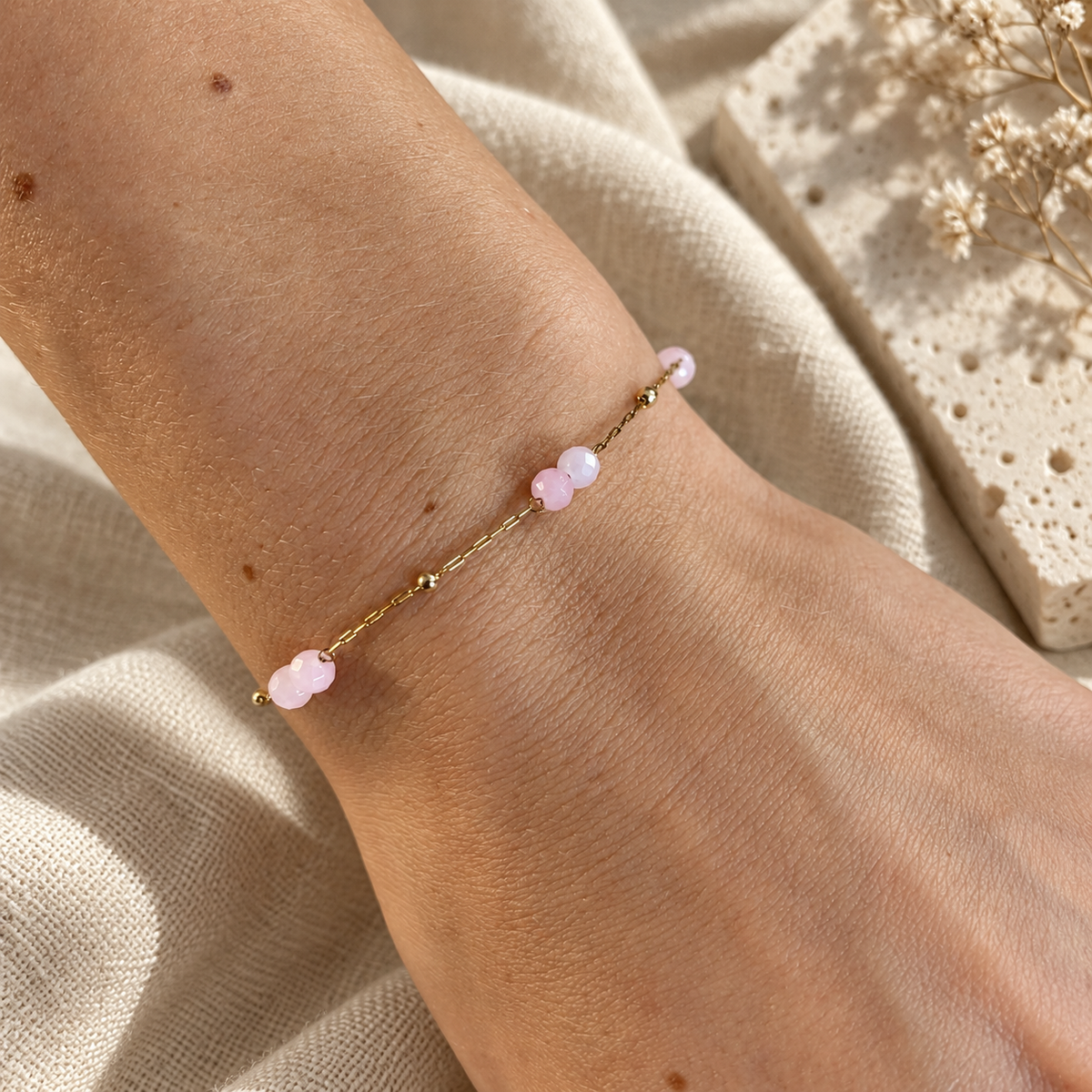 Goudkleurige armband Sola Lichtroze met roze steentjes om een pols