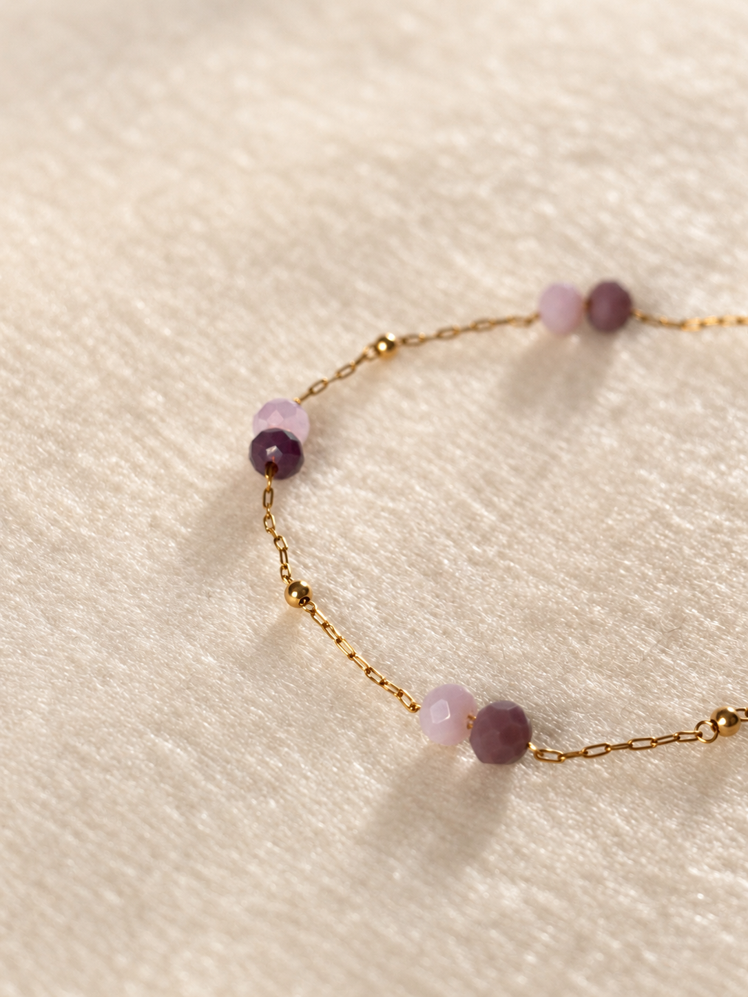 Detail van paarse kralen aan goudkleurige ketting Sola