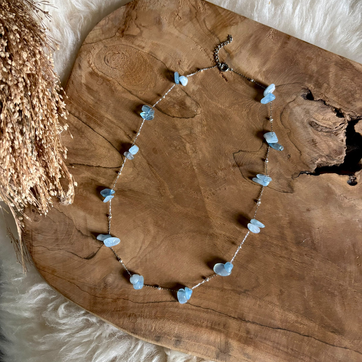 Zilverkleurige ketting Lumi met aquamarijn in een langere uitvoering op hout