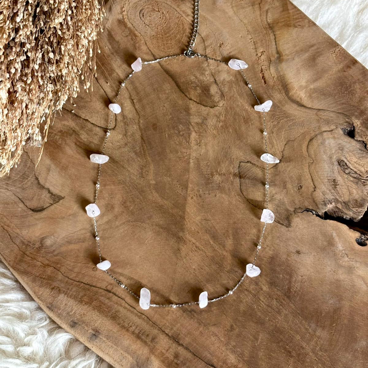 Zilverkleurige ketting Alba met rozenkwarts op een houten schaal