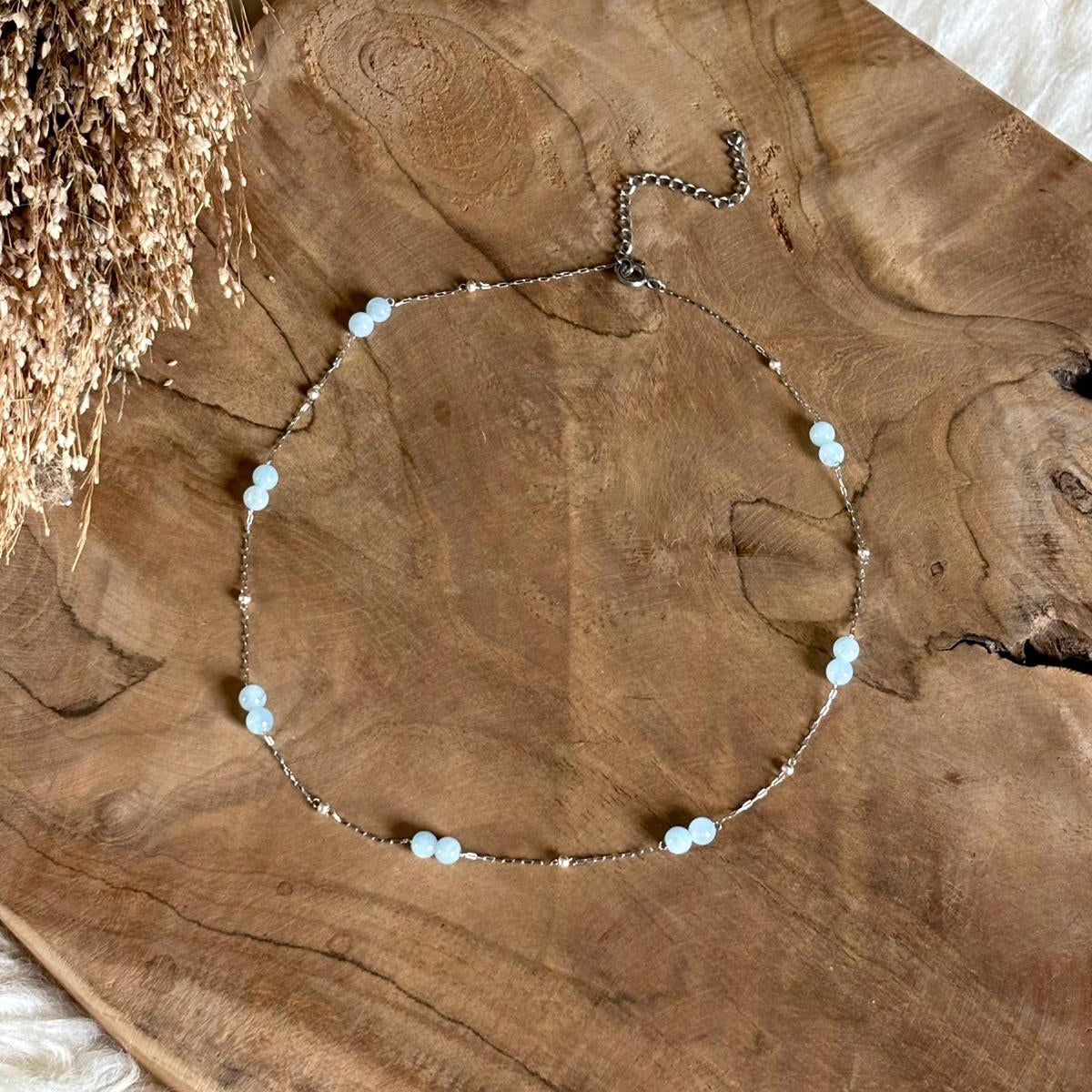 Zilverkleurige ketting Lumi met lichtblauwe aquamarijn op hout