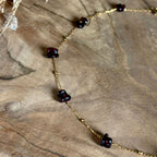 Detail van goudkleurige Lumi-ketting met granaatstenen