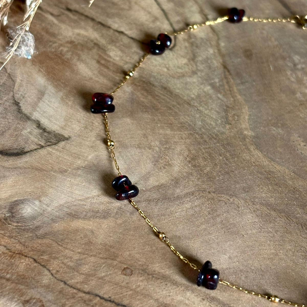 Detail van goudkleurige Lumi-ketting met granaatstenen
