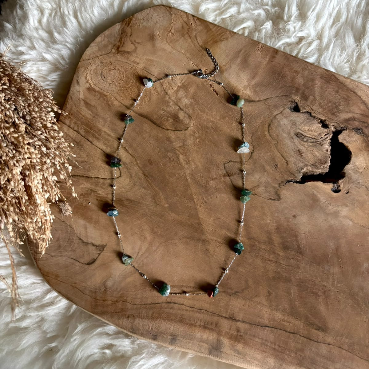 Zilverkleurige ketting Lumi met mosagaat in een langere uitvoering op hout