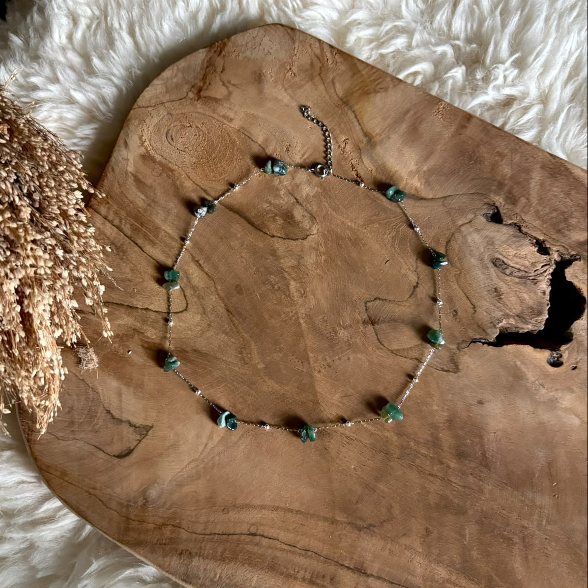 Zilverkleurige ketting Lumi met mosagaat op een houten plank