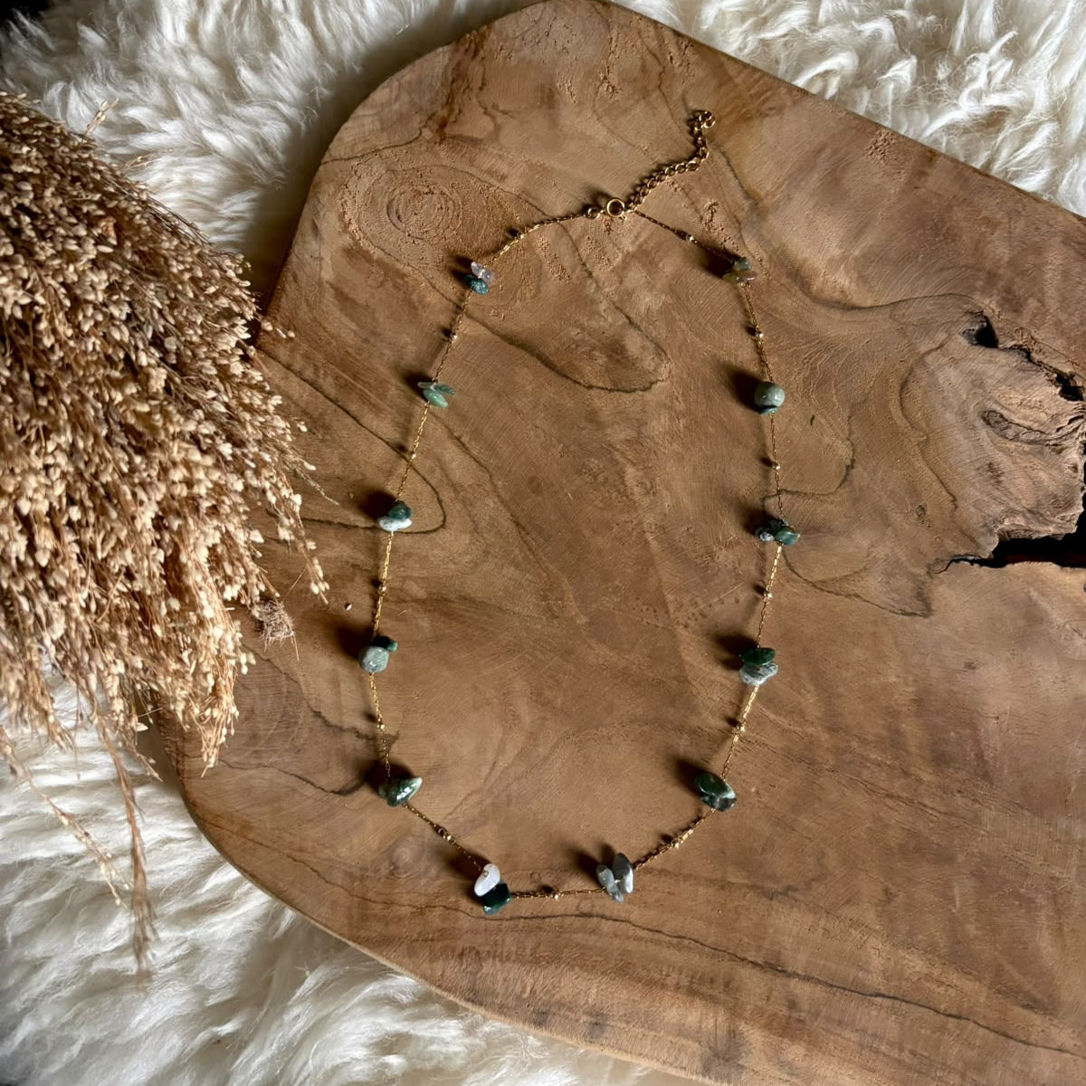 Goudkleurige ketting Lumi met mosagaat op een houten plank