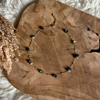 Goudkleurige ketting Lumi met mosagaat, liggend op hout