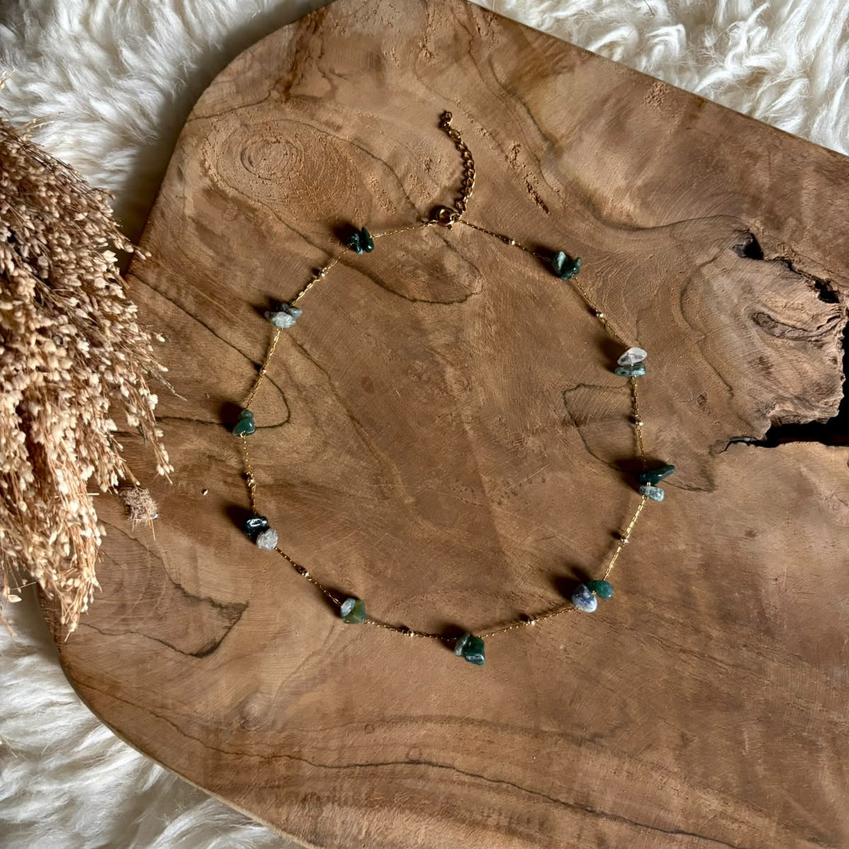 Goudkleurige ketting Lumi met mosagaat, liggend op hout